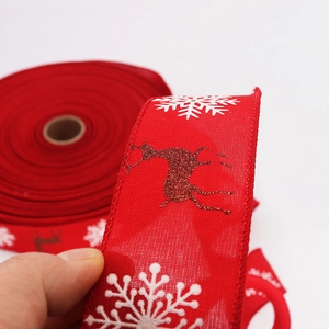 Close-up of red Christmas ribbon featuring white snowflakes and glitter reindeer patterns