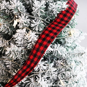 Close-up of red and black buffalo plaid ribbon with texture on snowy Christmas tree