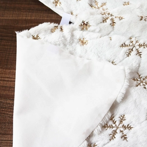 White plush Christmas tree skirt with golden sequin snowflakes and velcro fastener