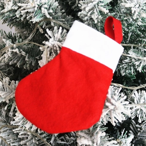 Classic red and white Christmas stocking ornament hanging on a snowy tree with lights