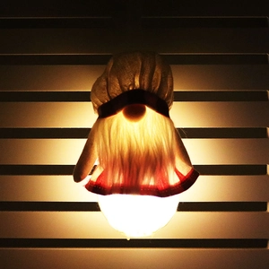 Détail d'un gnome de Noël avec chapeau tissé, barbe et socle LED à lueur chaude décoratif