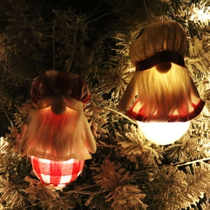 Détail de deux gnomes de Noël lumineux de 16cm avec LED suspendus sur des branches enneigées