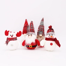 Close-up of five plush Christmas gnomes and reindeer decorations with LED lights