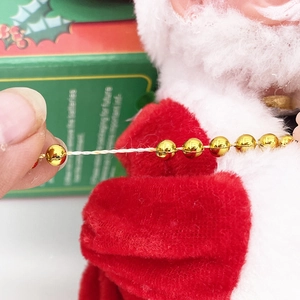 Detail showing Santa Claus plush suit and golden bead chain of the musical electric toy
