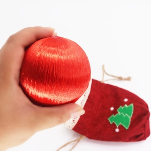 Close-up of red silk Christmas ornament and linen gift bag with green tree pattern