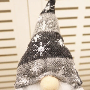Macro detail of knitted Christmas gnome hat with snowflake pattern and white beard