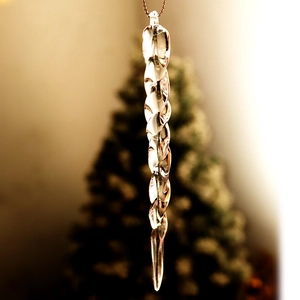 Macro detail of a clear acrylic spiral icicle ornament with metal chain on a Christmas tree