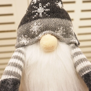Close-up of a Christmas gnome doll with gray knitted snowflake hat and white faux fur beard