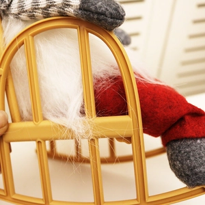 Detail of Christmas gnome plush doll in a yellow rocking chair with red felt hat
