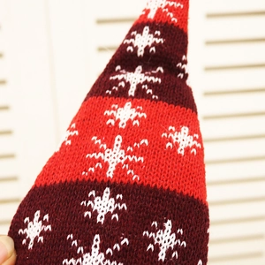 Detail of red and white knitted Christmas doll hat with snowflake jacquard pattern