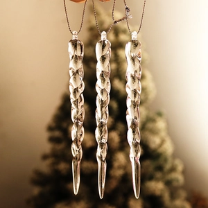 Close-up of three clear acrylic icicle ornaments hanging on a festive Christmas tree