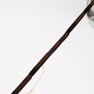 Detailed view of dark brown wood grain texture with vintage cord wrapping on a door sign