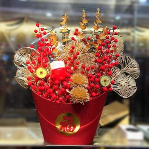 Chinese New Year flower arrangement with red berries and golden ginkgo leaves in a red bucket