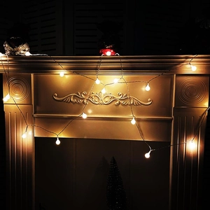 Warm white LED globe string lights hanging on a vintage fireplace for festive decoration