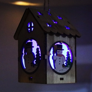 Dettaglio casa di Natale in legno con luce LED blu e ritagli a stella
