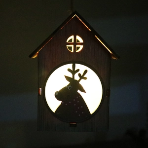 Dettaglio di casetta di Natale in legno con silhouette di renna e calda luce a LED