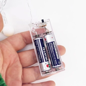 Detailed close-up of a clear plastic battery box for LED string lights with AA batteries
