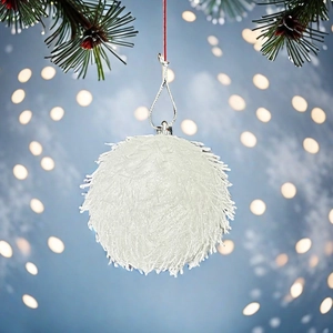 White glittery 8cm Christmas ball ornament hanging with pine needles and festive bokeh