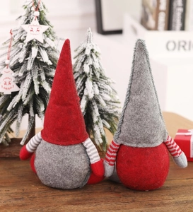 Handmade Christmas faceless gnome dolls in red and grey set on warm wooden table