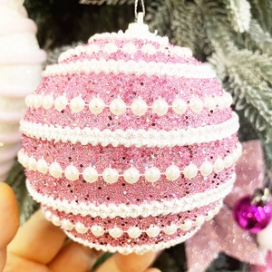 Vue détaillée d'une boule de Noël rose avec des perles et une texture pailletée