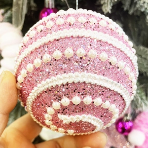 Vue détaillée d'une boule de Noël rose pailletée avec perles et dentelle blanche