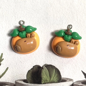 Detail of cute resin capybara charms with orange hat and leaf for DIY jewelry making