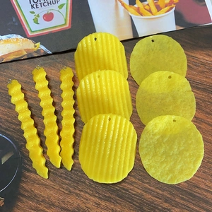 Détail macro de pendentifs réalistes en PVC de frites et chips jaunes pour bijoux DIY