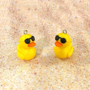 Close-up of yellow duck pendants with sunglasses and silver rings for DIY jewelry