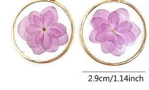 Détail de boucles d'oreilles rondes en résine avec vraies fleurs séchées violettes