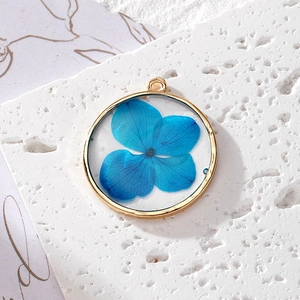 Pendentif circulaire en métal doré fait main avec de vraies fleurs séchées bleues en résine