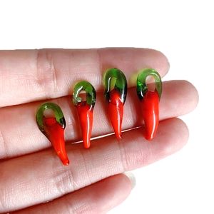 Handheld view of four handmade red glass chili pendants for DIY jewelry making