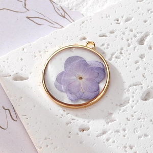 Vue macro d'un pendentif fleur séchée violette en résine avec cadre rond doré