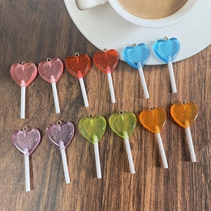 Macro view of colorful glitter resin heart lollipop charms on dark wood surface