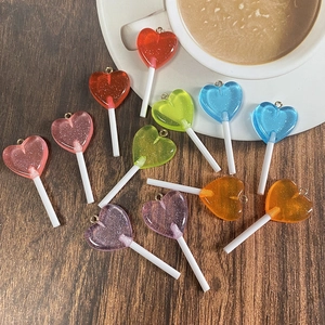 Colorful heart-shaped glitter lollipop charms scattered on a rustic wooden table