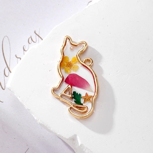Detailed close-up of handmade cat resin pendant with dried flowers and gold metal frame