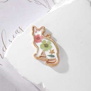 Detailed view of cat-shaped resin pendant with dried flowers and gold star inside