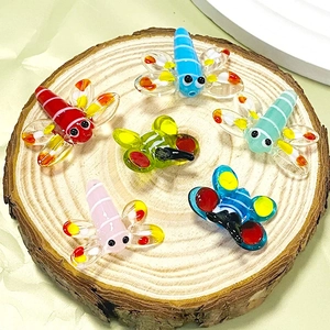 Colorful glass dragonfly charms for DIY jewelry making displayed on a wooden block