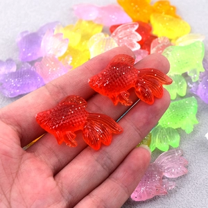 Dettaglio macro di ciondoli a forma di pesce rosso in resina colorata con glitter DIY