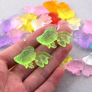 Dettaglio di ciondoli a forma di pesce rosso con paillettes colorate per gioielli fai-da-te