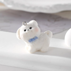Vista macro di un ciondolo a forma di cucciolo bianco floccato con fiocco blu