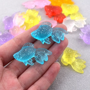 Dettaglio di ciondoli a forma di pesce in resina glitterata per gioielli fai da te