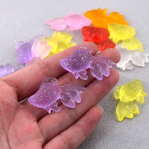 Dettaglio macro di ciondoli carpa koi glitterati con fori per creazione di gioielli