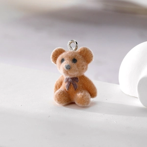 Detail eines braun beflockten Teddybär-Anhängers mit Schleife und Metallöse für DIY