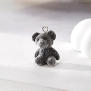 Makroaufnahme grauer beflockter Bärenanhänger mit Silberring für DIY-Schmuck