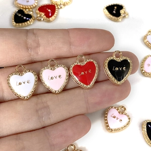 Colgantes de corazón Love en esmalte dorado para joyería DIY mostrados en la mano