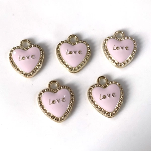 Detalle de colgantes de corazón en esmalte rosa con grabado Love y borde dorado