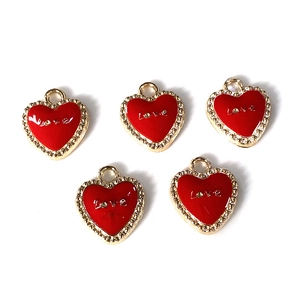 Detalle de cinco colgantes de corazón en esmalte rojo con letras Love doradas y borde ondulado