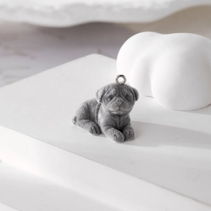 Detail of grey flocked pug dog pendant with silver metal ring on white geometric stand