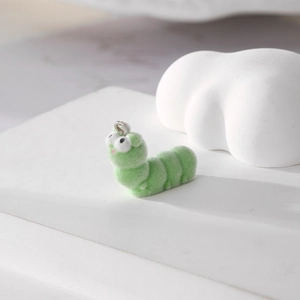 Macro detail of a fuzzy green caterpillar charm with soft flocking and metal ring