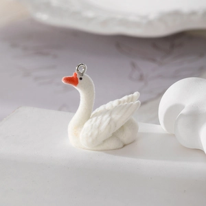 Detailed view of a white flocked swan charm with an orange beak and a metal loop